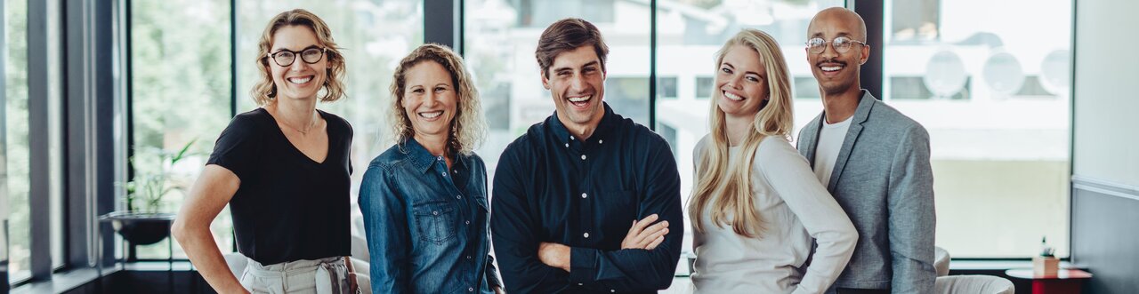 Kolleginnen und Kollegen stehen zusammen in einem Besprechungsraum